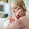 Baby with colic crying whilst mother holds them